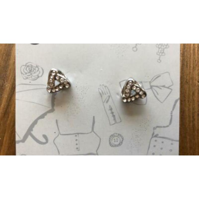 zilverkleurige oorbellen met witte steentjes erin