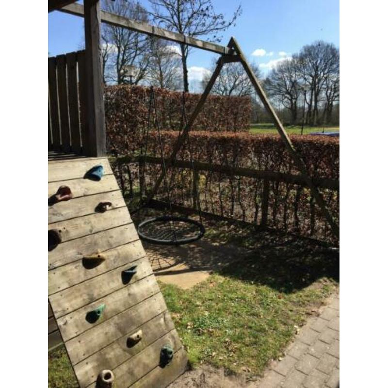 Speelhuis met glijbaan, klimwand en mand(nest)schommel.